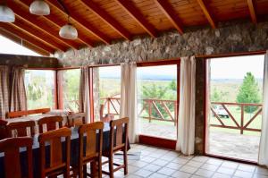 a dining room with a table and chairs and windows at Cabaña julian in La Cumbrecita