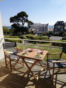 a wooden table and two chairs on a deck at Escapade Marine in Saint-Quay-Portrieux