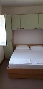 a bedroom with a bed with white sheets and a window at Apartments Andrijana in Drače