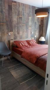 a bedroom with a bed with a red comforter and a chair at Les Floralies bis in Pau