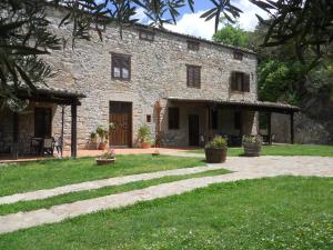 uma grande casa de pedra com um quintal relvado em frente em L'Antico Casale em Polizzi Generosa