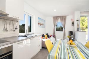 een keuken en een woonkamer met een tafel en gele stoelen bij Olive Eden Holiday Home in Milna