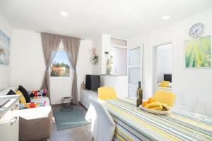 uma sala de estar branca com uma mesa e cadeiras amarelas em Olive Eden Holiday Home em Milna