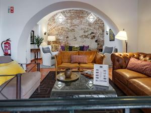 a living room with leather furniture and a brick wall at ADC - Albergaria Do Calvário - by Unlock Hotels in Évora