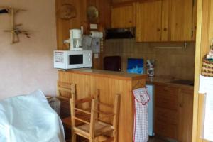 a kitchen with a microwave and a counter with two chairs at Appart en rez de jardin clos face au Mont BLANC in Combloux