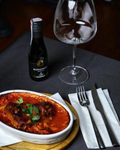 a table with a bowl of stew and a wine glass at Conti Hotel & Restaurant in Gjakove