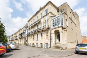 un viejo edificio con coches aparcados delante de él en 16 Lansdown -By Luxury Apartments, en Cheltenham