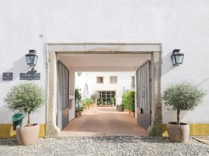 an entrance to a building with two trees in pots at ADC - Albergaria Do Calvário - by Unlock Hotels in Évora