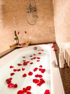 a bath tub filled with red flowers in a bathroom at Flame Hotel Boutique Canela in Canela