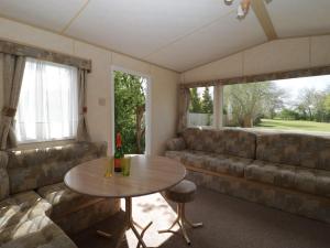 uma sala de estar com uma mesa e um sofá em The Coop - Family Friendly caravan near Glastonbury & Street em Compton