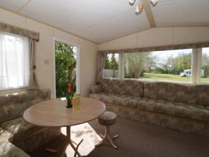 uma sala de estar com um sofá e uma mesa em The Coop - Family Friendly caravan near Glastonbury & Street em Compton