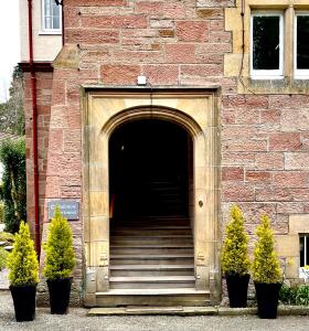 einen Eingang zu einem Backsteingebäude mit Treppen und Pflanzen in der Unterkunft Rossal House Apartments, Inverness, Highlands in Inverness