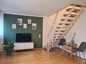 sala de estar con escalera y TV de pantalla plana en Ferienwohnung FüssenPur, en Füssen