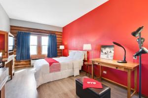 a bedroom with a red wall with a bed and a desk at Casa Loma Inn & Suites by OYO Davenport IA near I-80 in Davenport