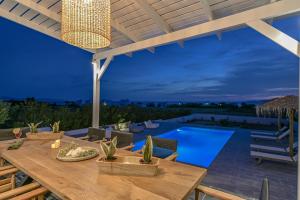an outdoor dining area with a table and a swimming pool at Villa Tranquillity in Kastraki Naxou