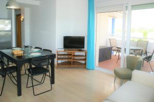 a living room with a table and a television at Apartamento con vistas al canal en residencia con piscina in Roses