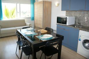 a kitchen and living room with a table and a microwave at Apartamento con vistas al canal en residencia con piscina in Roses