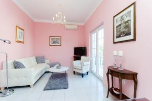 een woonkamer met een witte bank en een roze muur bij Apartments Sinisa Malinska in Malinska