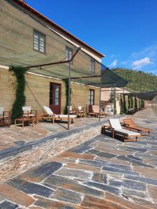 a stone patio with benches and a building at Quinta da Caída in Arcas