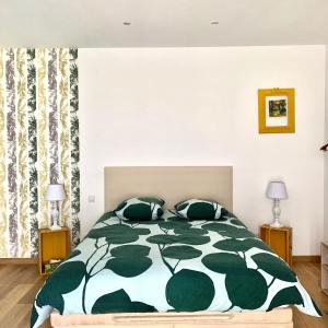 a bedroom with a bed with a green and white comforter at Atelier des Vidaux in Saint-Aunès