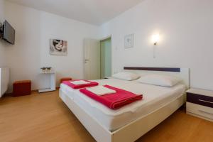 ein Schlafzimmer mit einem großen weißen Bett mit roten Handtüchern darauf in der Unterkunft Apartments Zorica in Dramalj
