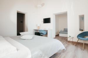 a white bedroom with a bed and two blue chairs at A-mare Exclusive Rooms & Suites in Taranto