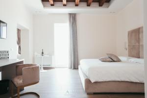 a bedroom with a bed and a chair and a window at A-mare Exclusive Rooms & Suites in Taranto