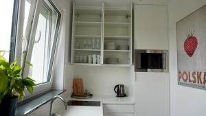 una cocina con armarios blancos y una ventana en Apartament Osiedle Zielone, en Chmielno