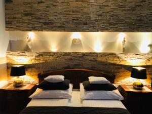 two beds in a room with two lamps and a stone wall at Apartamenty Blisko Centrum in Toruń