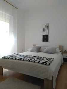 a white bedroom with a large bed with a zebra blanket at Doana Apartments in Vir
