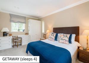 a bedroom with a bed with a blue blanket and a desk at Cadnam Lodge in Cadnam