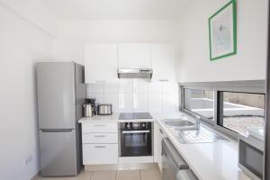 a white kitchen with a sink and a refrigerator at Esprit Villa 30 in Polis Chrysochous
