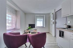 uma cozinha com duas cadeiras roxas num quarto em Appartement 2 pièces pleins de charmes (Géorgie) em Audincourt