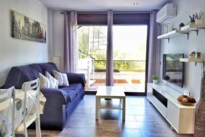 uma sala de estar com um sofá azul e uma mesa em Barbacoa + vistas al mar + playa + piscina. em Salou