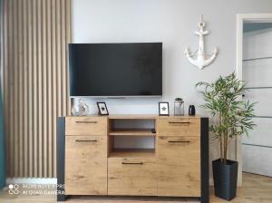a television on a wooden dresser in a living room at Apartament Baltic13 in Gąski