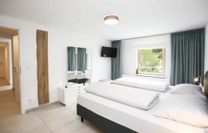 a white bedroom with two beds and a window at Ferienhaus Münzberg in Annweiler am Trifels