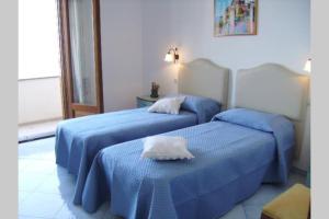 two beds in a hotel room with blue sheets at Blumavy in Praiano