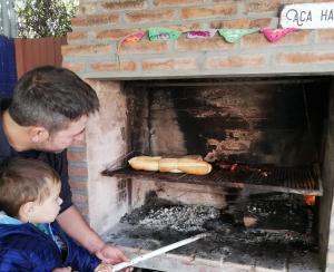 Un uomo e un ragazzo che cucinano hot dog su una griglia di Alojamiento familiar a Coronel Suárez