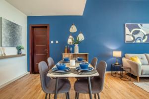 a dining room with blue walls and a table and chairs at Live Modern Live Luxury - Dubai Studio City in Dubai