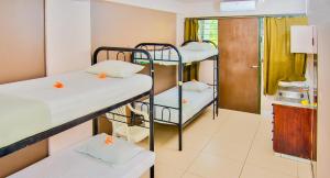 a room with three bunk beds and a kitchen at Bamboo Backpackers in Nadi