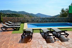 a swimming pool with chairs and a table next to it at Villa Rosa in Canillas de Albaida