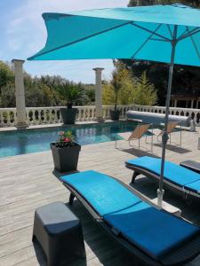 a pool with two blue lounge chairs and an umbrella at Appartement Pinede Man Yelle in Sanary-sur-Mer