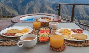 a table topped with plates of food and cups of orange juice at Monteza Lujo Natural in Piedecuesta