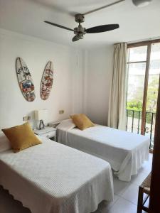 a bedroom with two beds and a ceiling fan at Port Pollensa Pins Apartment sea view in Port de Pollensa