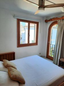 a bedroom with a large bed with two windows at Port Pollensa Pins Apartment sea view in Port de Pollensa
