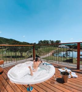 a man sitting in a bath tub on a deck at BANGALÔS REFÚGIO DO VALE in Santa Maria do Erval