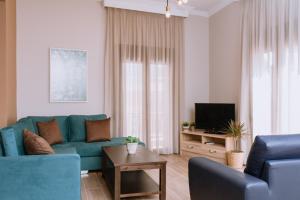 uma sala de estar com um sofá azul e uma televisão em Ιlektra's House em Kavala