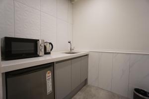 uma cozinha com um micro-ondas e um lavatório em EKklim Classic Hotel em Pyeongtaek