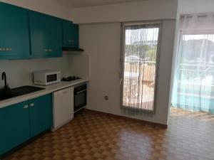 a kitchen with green cabinets and a microwave and a window at Marina Port Camargue in Le Grau-du-Roi
