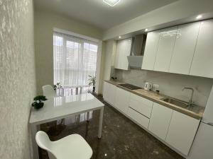 una cucina con armadi bianchi e una sedia bianca di 2 кімнатні ,Люкс апартаменти в ЖК Арена ,район автовокзалу a Rivne